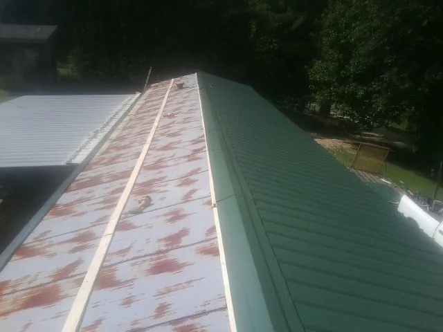 Old rusted panels beside newly installed green metal roofing — Wind Damage Roof Repair by Roofing Brothers in Saint Helena