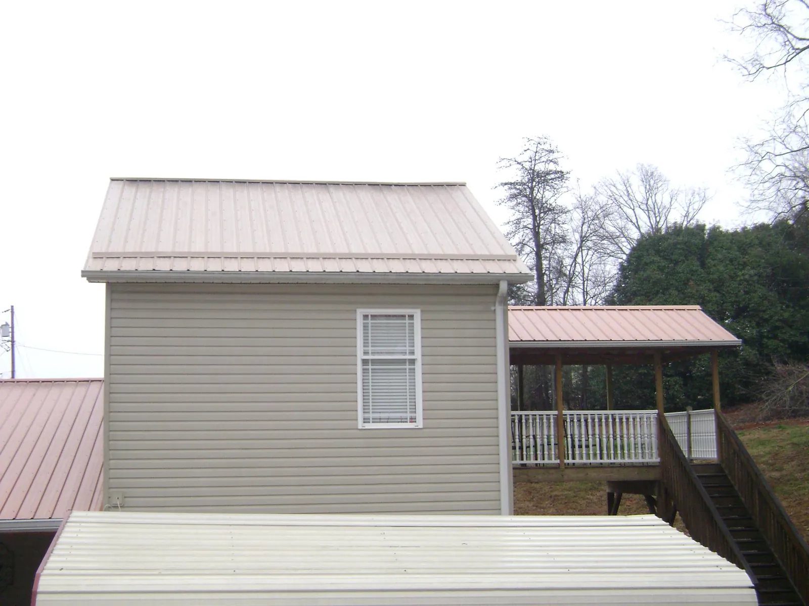 Tan metal roofs on a two story addition and attached porch, from a Roof Replacement job in Saint Helena